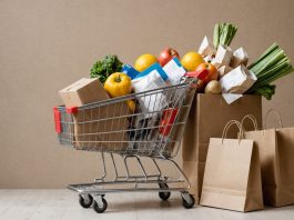 Grocery cart next to shrinking shopping bags representing consumer spending cuts